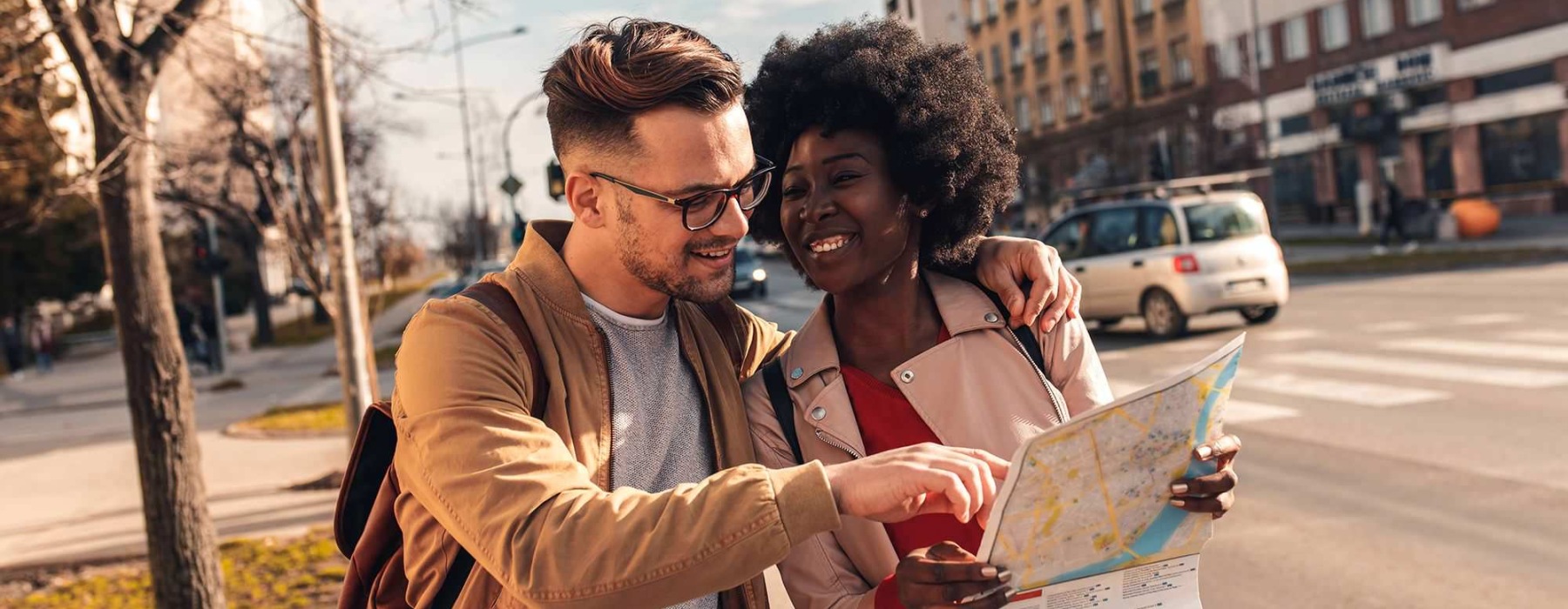 a man and woman walk together on a sidewalk while looking at a map